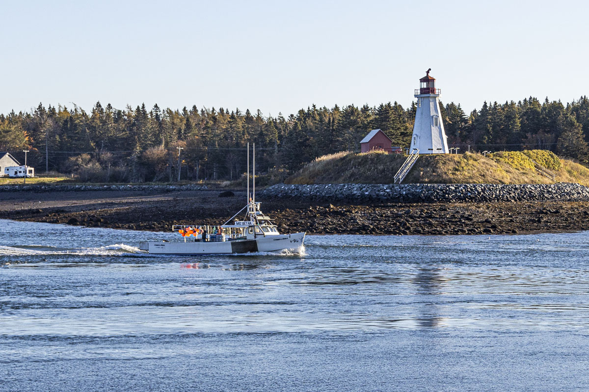A boat moves past the privately owned decommissioned Mulholland Point Light on Canada's Campobello Island [S75R2976]